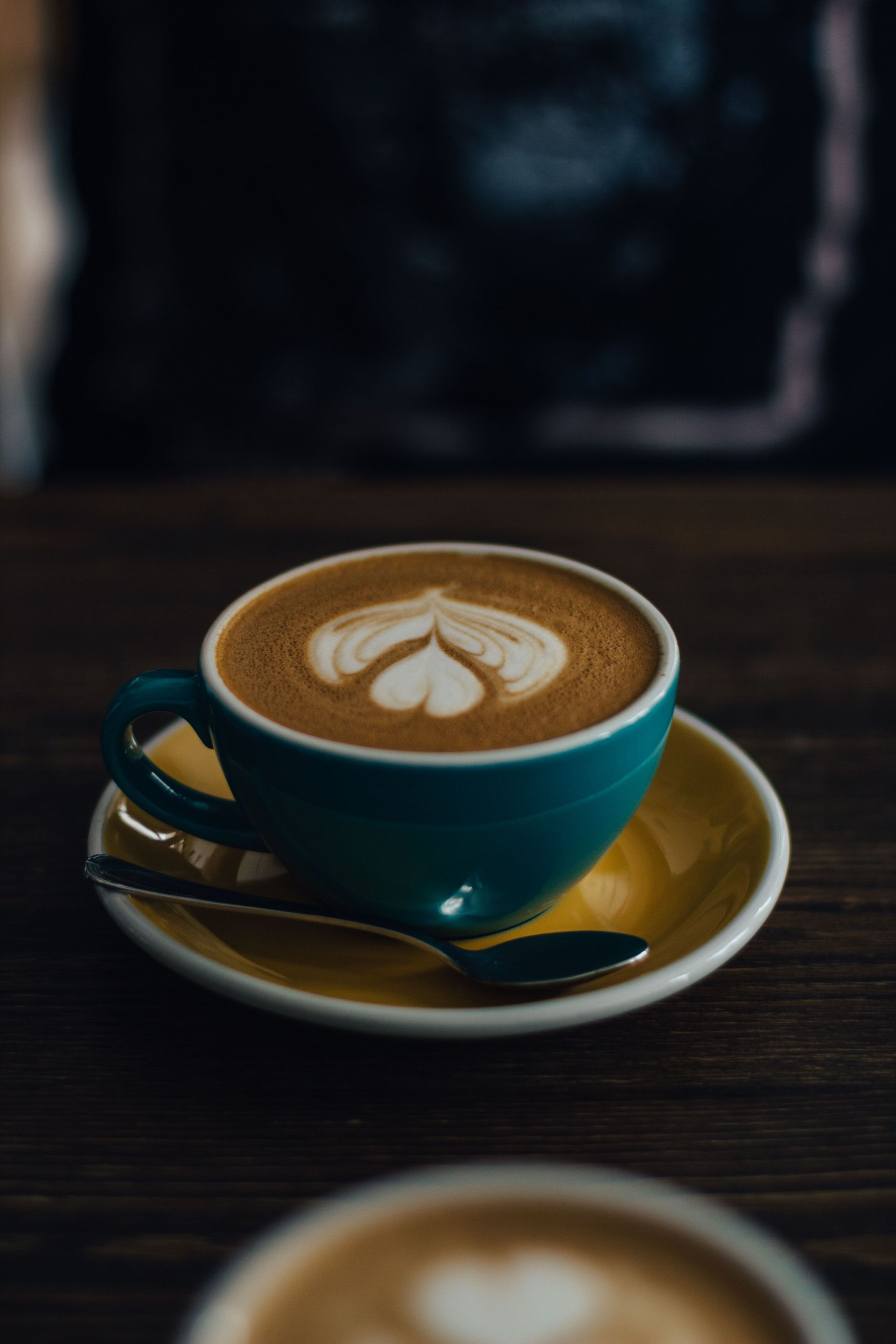 Close-up of latte art in a turquoise cup on a wooden table, perfect for café-themed imagery.